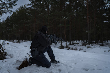 A border guard special forces soldier takes aim with an assault rifle with a red dot sight in a...