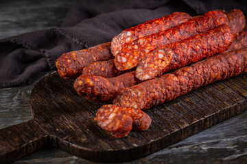 Fototapeta premium Smoked paprika sausage sticks on a wooden board, appetizer and charcuterie s