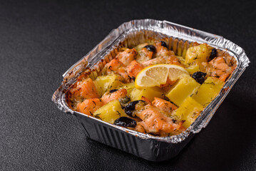 Baked salmon pieces with potatoes, cheese and olives