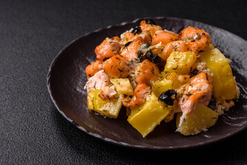 Baked salmon pieces with potatoes, cheese and olives