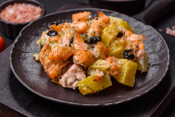 Baked salmon pieces with potatoes, cheese and olives