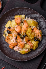 Baked salmon pieces with potatoes, cheese and olives