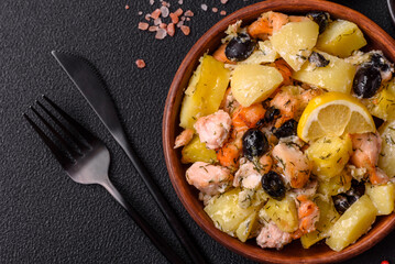 Baked salmon pieces with potatoes, cheese and olives