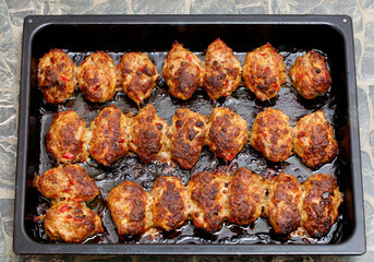 A tray of meatballs is cooked in a pan