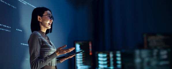 asian woman programmer standing in front of a screen with code projected  presentation the integration of technology and human expertise in software development