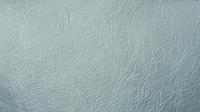 Detailed macro footage smooth white leather surface highlights elegant texture slow panning motion creating luxurious backdrop 4K