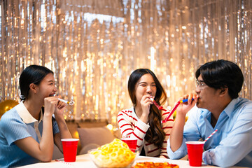 Three friends joyfully celebrating drinking eating drinking and cheerful expressions at house party
