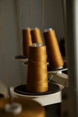A close up of a golden spool of thread on tailor machine plate tube. 