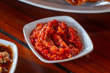 Traditional indonesian mortar chili and tomato sauce (sambal uleg tomat), made with fresh chili, garlic, onion, and tomato, served on small bowl