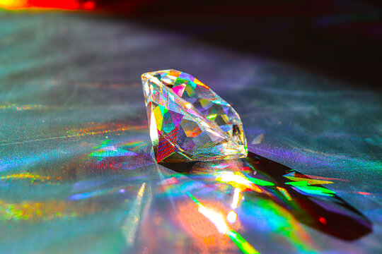 Holographic fabric texture. A diamond lies on a shiny fabric. Rainbow effect. Prism.