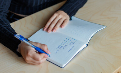 Woman leaning Chinese language with handwriting Chinese characters in notebook.