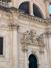 Obraz premium Close up detail and ornamentation photograph of the entrance and pediment over the door capped with an angel sculpture at St. Ignatius Church in Old Town in Dubrovnik Croatia. High quality photo