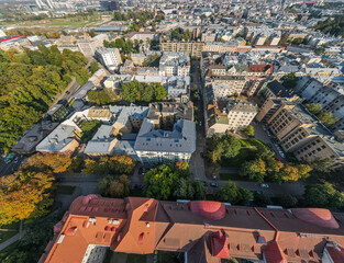 Aerial perspective of a city featuring red roofed buildings, tree lined streets, light colored...
