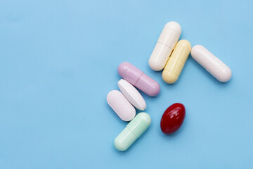 Colorful capsules and pills on blue background.