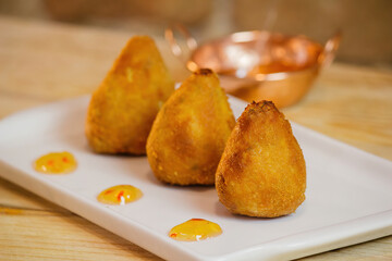 drumsticks of various flavors on a white plate with a bronze pan behind on a wooden table with...