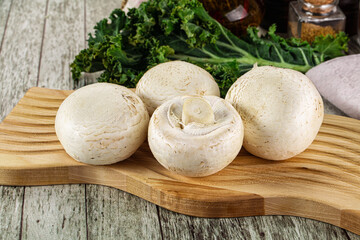 White champignon mushrooms heap over board