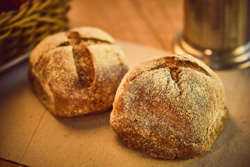 Photo of bread on a table in a wooden bar or restaurant with a paper base and surrounded by a mug of coffee and a jar of sugar and a basket of condiments prepared for breakfast or afternoon