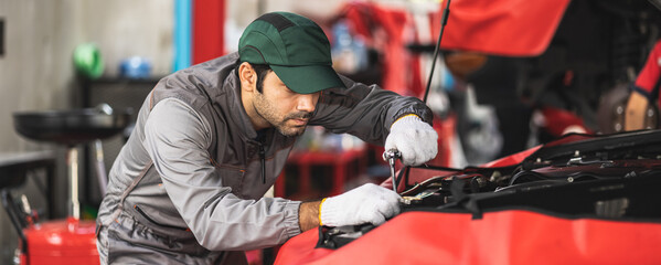 Obraz premium A skilled professional mechanic checks the engine oil for peak performance. Dedicated to service and repair, Technician inspecting and maintaining the engine of a car or vehicle