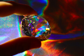 Holographic fabric texture. A diamond lies on a shiny fabric. Rainbow effect. Prism.