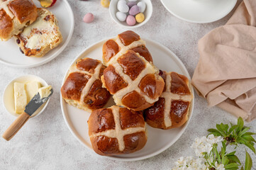 Traditional Easter hot cross buns on a white plate with butter, berry jam and cup of tea. Delicious...
