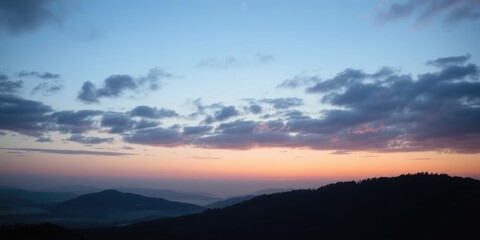 Obraz premium Serene mountain landscape at dawn, showcasing a breathtaking panorama of pastel-hued sky and hazy silhouettes of distant hills