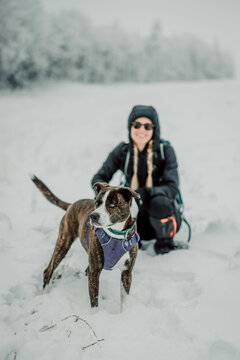 one woman posing with dog while walking in the snow, maine.