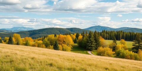 Serene autumnal landscape featuring a winding path through golden foliage and a backdrop of majestic mountains under a partly cloudy sky
