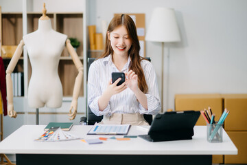 Fashion designer woman talking smart phone and using laptop with digital tablet computer in modern...