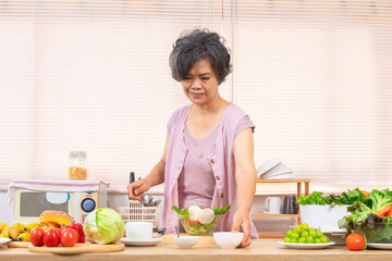 Asian senior woman lifestyle healthy food, elderly retirement joyful living at home making vegetable salad for breakfast in domestic kitchen, silver hair female in 70s holiday activities eating fruits