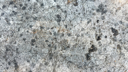 Fototapeta premium Gray stone floor with black dots. Rough and hard surface with cracks on the stone face. Stone background. Abstract background.