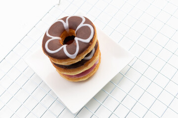 A stack of three glazed donuts on white table background.