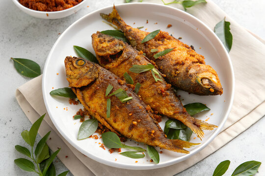 Indian-style red masala grilled fish fry with aromatic roasted coriander on a white plate, ideal for culinary presentations.