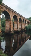 Fototapeta premium Majestic stone arch bridge reflecting on calm waters.