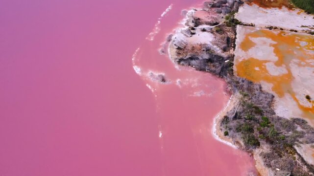 Sunset casts a warm glow over the torrevieja pink lake shore, highlighting the vibrant salt flats and colorful waters