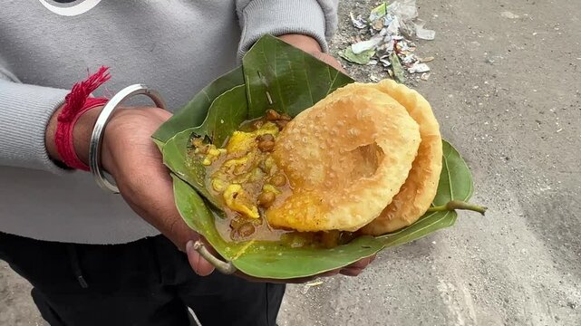 Dal puri and sabji served in Sakua leaves on hands of a customer at early morning in Ranchi, Jharkhand.