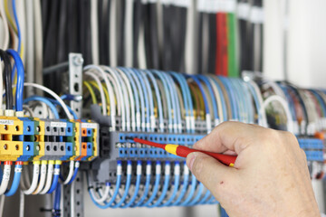 Installation of mounting wires in an electrical switchboard using a screwdriver.