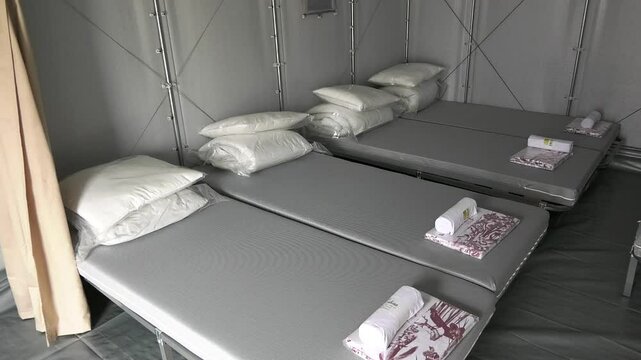 Beds with pillows and bed linen in a modular refugee house. Humanitarian aid to refugees, people affected by the war.