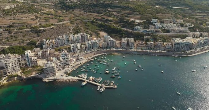 Scenic Aerial View of Bugibba Malta Marina with Mediterranean Coastline Cityscape and Moored Yachts Ideal for Travel and Tourism in Europe. High quality 4k footage