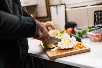 Close up of professional chef preparing ingredients  for vegetarian meal in restaurant's kitchen. He is cutting cauliflower.