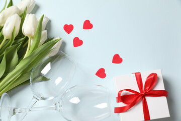 Valentine's day dinner concept. Top view table with setting for romantic dinner, wine glasses, white gift box, confetti. Valentines card. 