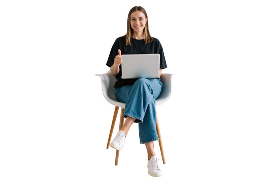 cheerful young woman sitting on a chair, working on a laptop, giving a thumbs-up gesture.