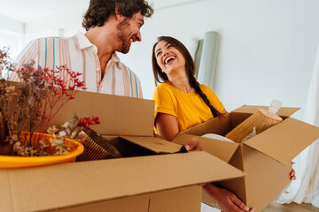 Happy young couple relocating in a new apartment. Young woman and man working and arranging the new...
