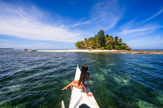 Young asian woman in bikini on boat prow, Guyam island, Siargao