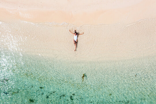 Aerial view of young woman lying down on a sandy beach, Philippines