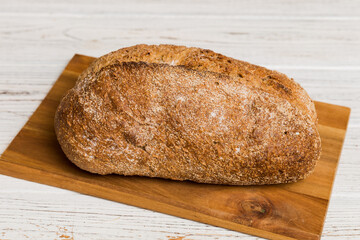 Freshly baked bread on cutting board against white wooden background. perspective view bread with copy space