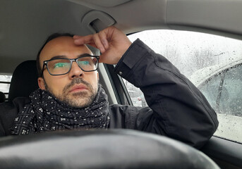 Autista alla guida della propria automobile in una giornata di pioggia in inverno	