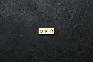 OKR word written on wood block. abbreviation of Objective Key Results text on cement table for your...