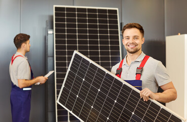 Happy and smiling man, a worker, is depicted holding a solar panel. This portrait captures his...