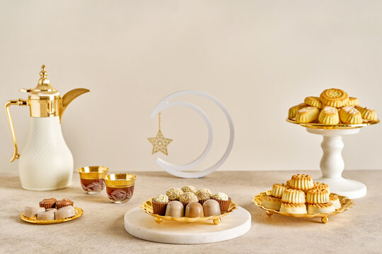 Assorted semolina maamoul or mamoul cookies , chocolate candy , awameh or lokma with dallah and ramadan decor crescent moon. Traditional arabic Eid al Adha, Eid al Fitr , Ramadan sweets