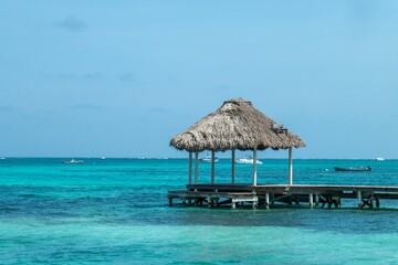 Tropical beach scene with a thatched-roof hut over turquoise waters.